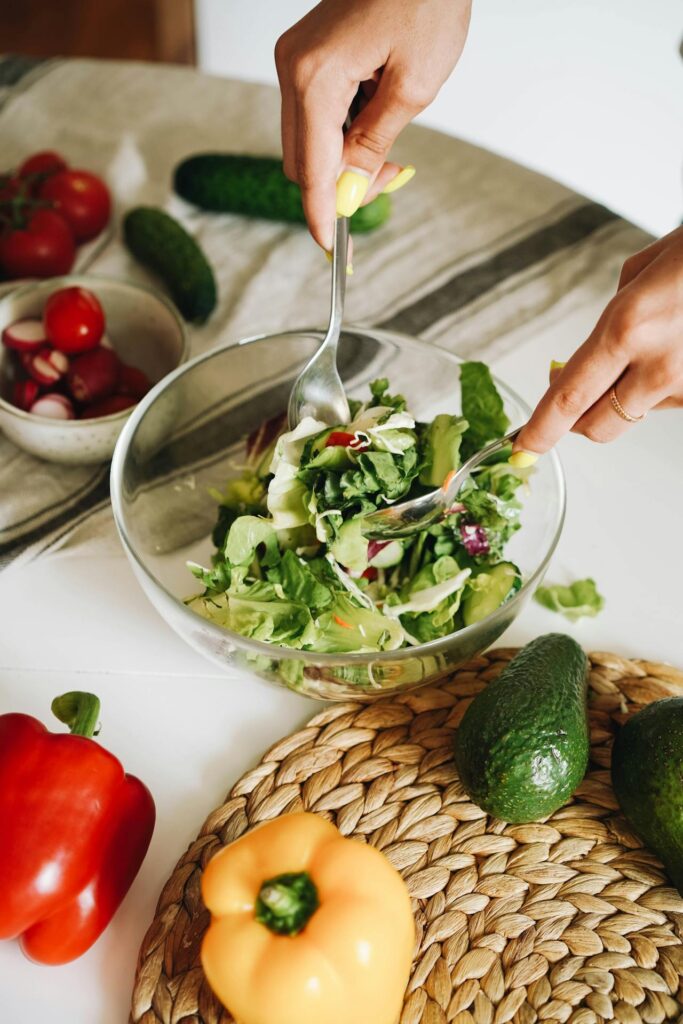 A person eating a salad from a bowl of salad